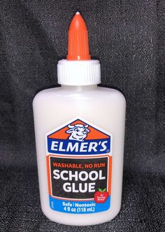 a bottle of school glue sitting on top of a black cloth