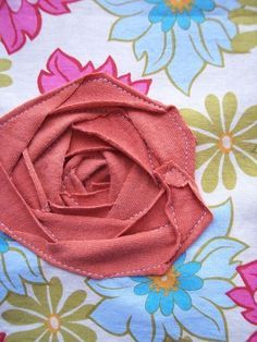 a pink flower is laying on top of a floral print fabric material that has been stitched together