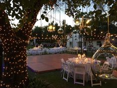 an outdoor venue with tables and chairs set up for a formal dinner under the trees