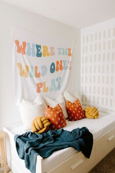 a bed with pillows and blankets on top of it in a bedroom next to a wall hanging