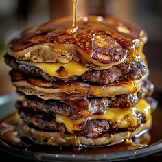 a stack of pancakes covered in syrup and cheese on top of a black plate with a fork