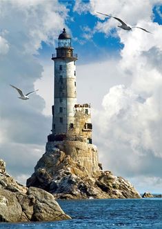 two seagulls are flying around a lighthouse