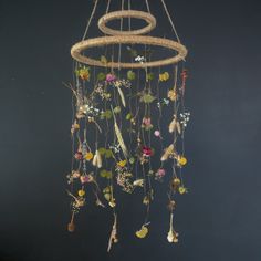 a wind chime with flowers hanging from it's sides on a black wall