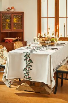 a dining room table is set with place settings and candles on the table, along with other furniture