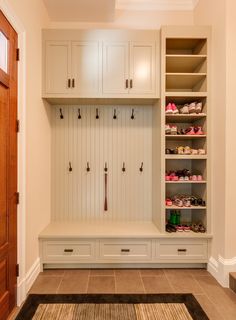 a large white closet with lots of shoes on the shelves next to an open door