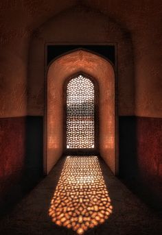 the shadow of a light shining through a window in an old building with red walls