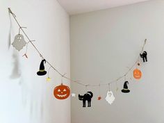 halloween decorations are hanging on the wall in this white room with orange and black pumpkins