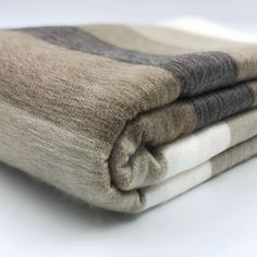 two blankets folded on top of each other with white and grey stripes in them,