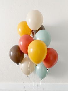 a bunch of balloons floating in the air on top of a table next to a wall