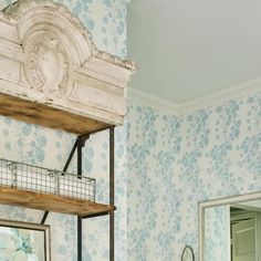 a bathroom with blue and white wallpaper and shelves above the toilet, mirror and sink