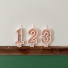 three candles with the numbers 123 and 123 on them are sitting in front of a green wall