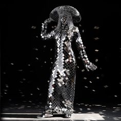 a woman in a silver dress and hat with lots of confetti on the floor