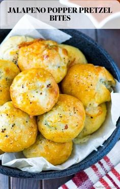 a bowl filled with cheese rolls on top of a wooden table next to a red and white checkered napkin