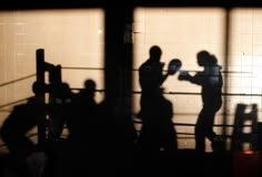 the shadow of two people boxing in a ring with shadows on the wall behind them