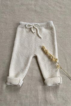 a white knitted baby's pants with a flower on the side