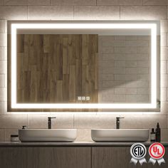 a bathroom with two sinks and a large mirror above it that is illuminated by lights