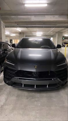 two cars parked in a parking garage with their hoods down and the lights on