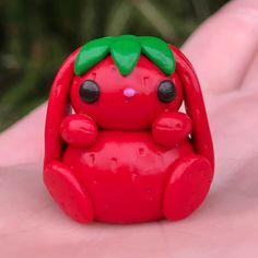 a small red toy sitting on top of a persons hand