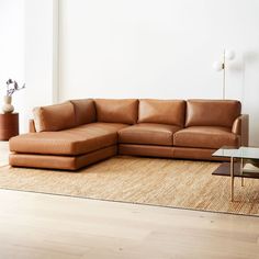 a brown leather couch sitting on top of a wooden floor next to a glass table