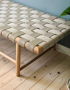 a wooden bench sitting on top of a hard wood floor next to a potted plant