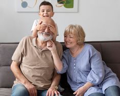 an older man sitting on top of a woman's lap while holding a child