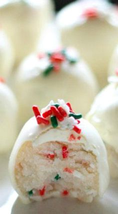 a white plate topped with cake balls covered in frosting and sprinkles