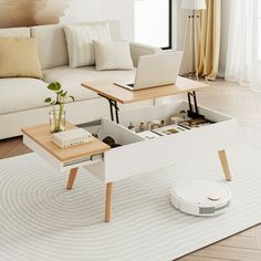 a living room with a couch, coffee table and laptop on top of it in front of a window