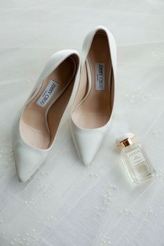 a pair of white shoes next to a bottle of perfume