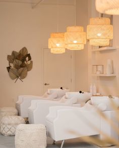 a living room filled with white furniture and hanging lights