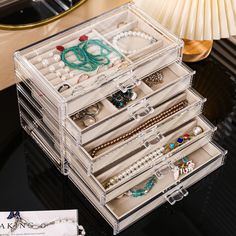 an assortment of jewelry sits on a black table next to a lamp and a card holder