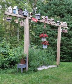 a garden with lots of bird houses hanging from it's sides