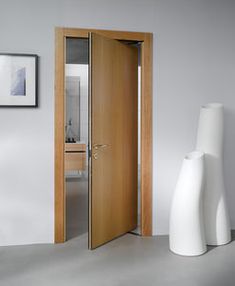 an open door in a white room next to a vase