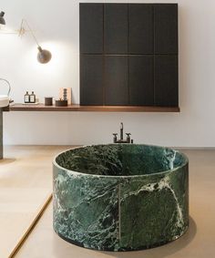 a marble sink in the middle of a room with wooden shelves and lighting above it