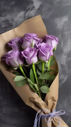 a bouquet of purple roses wrapped in brown paper