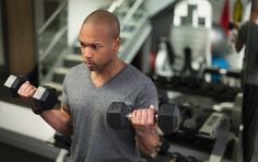 a man lifting two dumbs in a gym