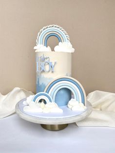 a blue and white cake sitting on top of a metal stand next to a white table cloth