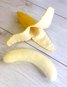 a peeled banana sitting on top of a white wooden floor next to a cut in half banana