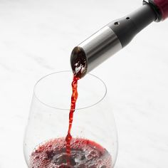 a wine glass filled with red liquid being poured into it