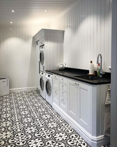 a washer and dryer in a white laundry room with black counter tops on the floor