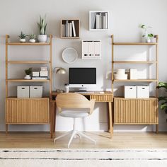 a desk with a computer on top of it in front of a wall mounted bookshelf