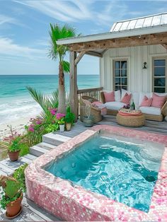 a hot tub sitting on top of a wooden deck next to the ocean in front of a house