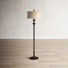 a floor lamp with a white shade on it in a living room or dining room