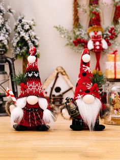 two red and white gnomes sitting on top of a wooden table next to each other