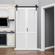 an empty kitchen with white cabinets and black hardware on the sliding doors that are open