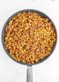 a skillet filled with ground beef and corn on top of a white countertop