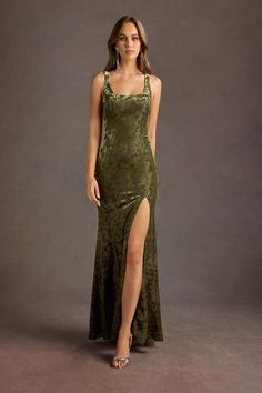 a woman wearing a green dress with a slit down the side and high heels on her feet