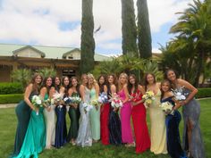 a group of beautiful women standing next to each other on top of a lush green field