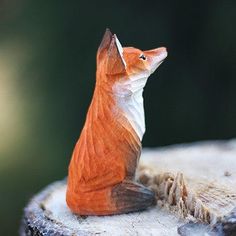 a figurine of a fox sitting on top of a tree stump