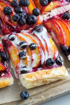 blueberries and peaches are on top of puff pastry