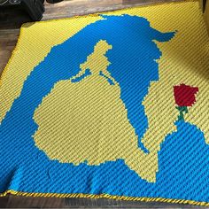 a crocheted map of the world with a red rose on yellow and blue